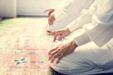 Müslüman erkeklerin dua Teşehhüt duruş, halının üzerinde oturan insanların kırpılmış görüntü