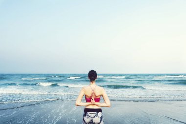 Kadın plajda yoga yapıyor.