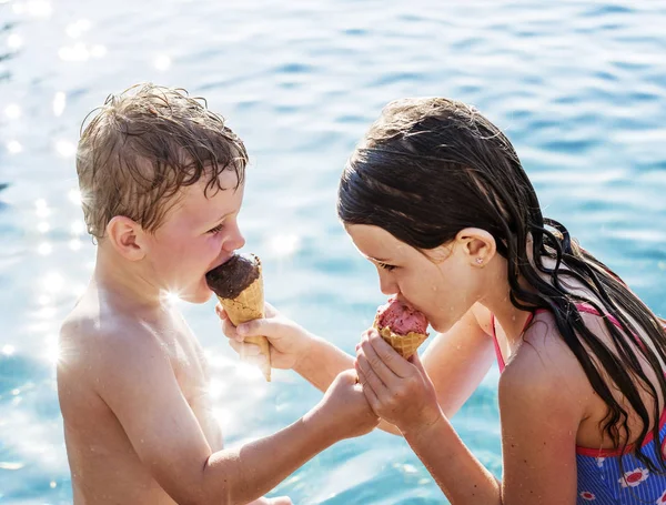 Child sharing an ice cream by the pool