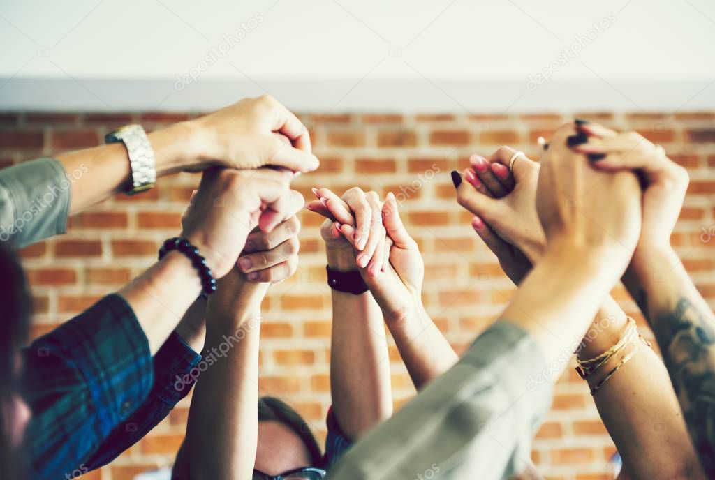 cropped shot of group of people holding hands in support