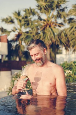 Bir bardak şarap havuza sahip yakışıklı adam