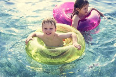 Neşeli erkek ve kız kardeşler havuzda yüzüyor