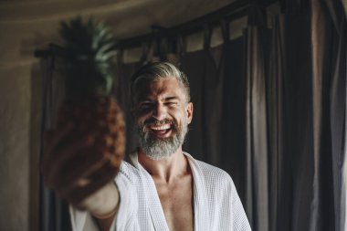 Bir ananas tutan bornozlu adam