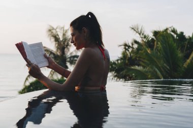 Kadın yüzme havuzunda bir kitap okuma