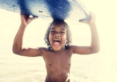 Sörf tahtası taşıyan küçük bir çocuk