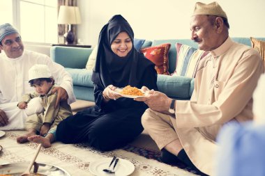 Muslim family having dinner on floor, celebrating Ramadan clipart