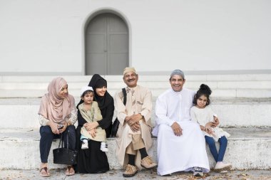 Muslim family sitting together outdoors clipart