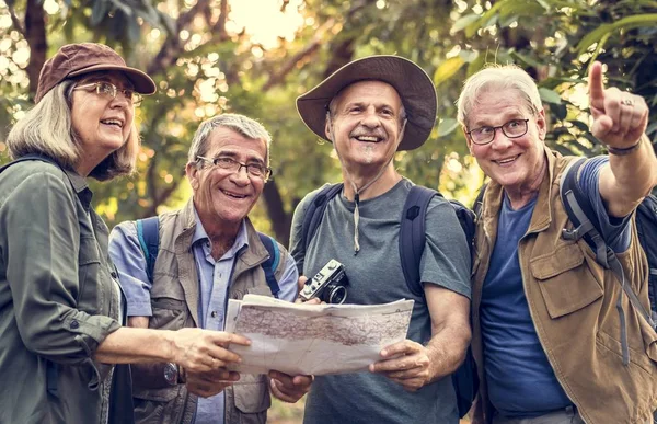 Mature people with map in forest, man pointing finger on way