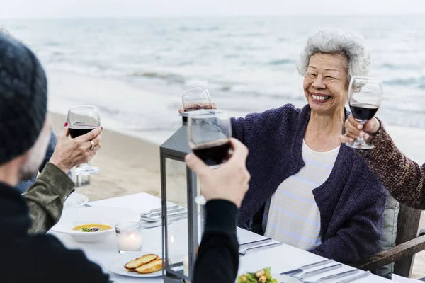成熟的朋友在海滩喝葡萄酒 — 图库照片