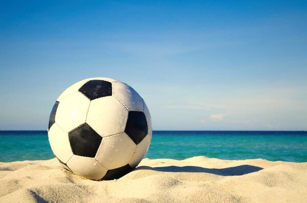 Football ball on tropical sandy beach at sea water 