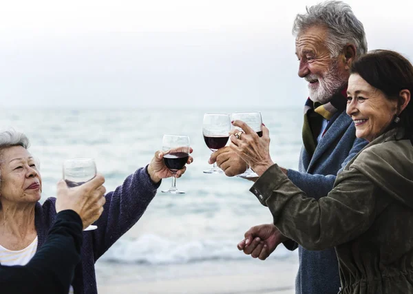 成熟的朋友在海滩喝葡萄酒 — 图库照片