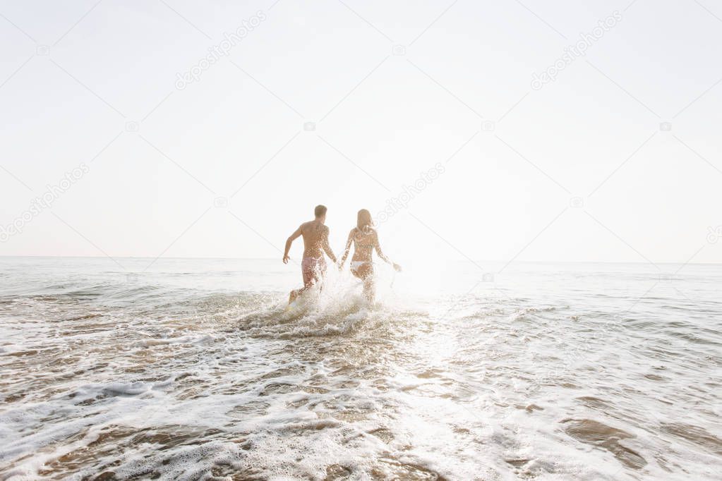 Happy couple running into the water