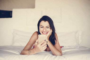 Yatakta bir cep telefonu kullanan kadın