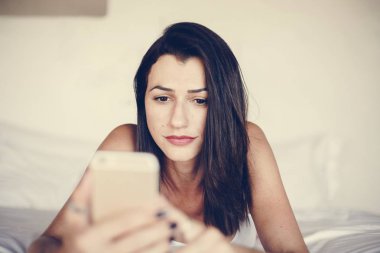 Yatakta bir cep telefonu kullanan kadın