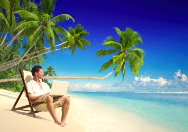 Genç adam sahilde dizüstü bilgisayar ile çalışma 