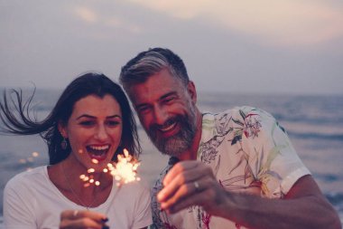 Couple celebrating with sparklers at the beach clipart