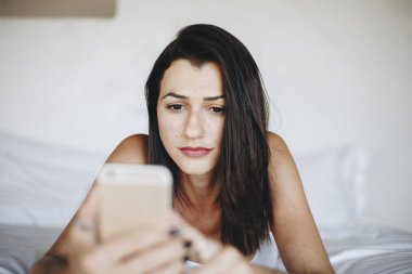 Yatakta bir cep telefonu kullanan kadın