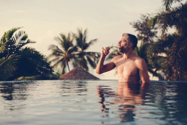 Bir bardak şarap havuza sahip yakışıklı adam