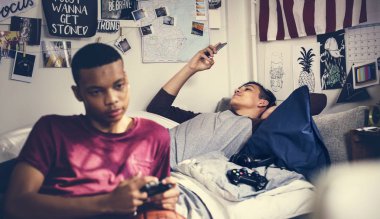 Genç çocukların bilgisayar oyunu oynamak ve bir smartphone kullanarak bir yatak odasında takılmak