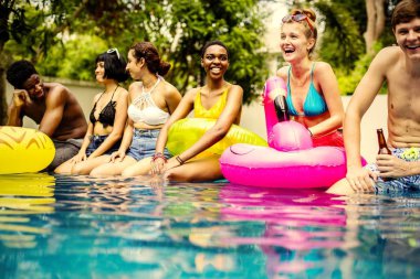 Bir yüzme havuzunun kenarında oturan arkadaşlar