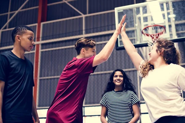 一群十几岁的朋友在一个篮球场给对方一个高五 — 图库照片