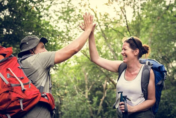 森でハイキングしながらハイタッチを与える幸せな笑みを浮かべてカップル — ストック写真