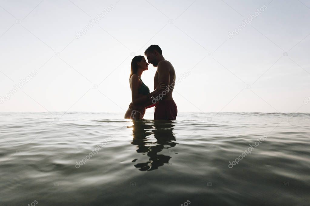 Romantic couple in the sea at sunset