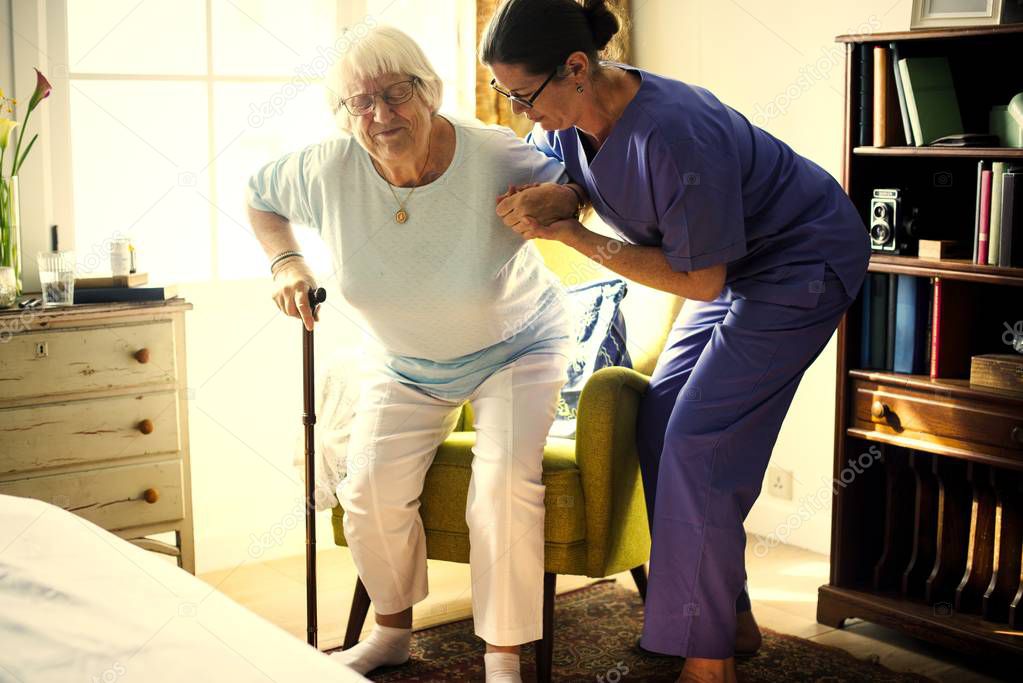 Nurse helping senior woman to stand up