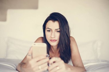 Yatakta bir cep telefonu kullanan kadın