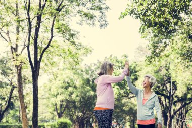 Çak bir beşlik veren Park iki üst düzey kadın arkadaş 