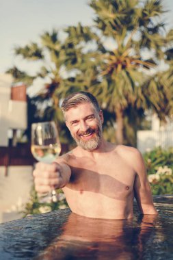 Bir bardak şarap havuza sahip yakışıklı adam