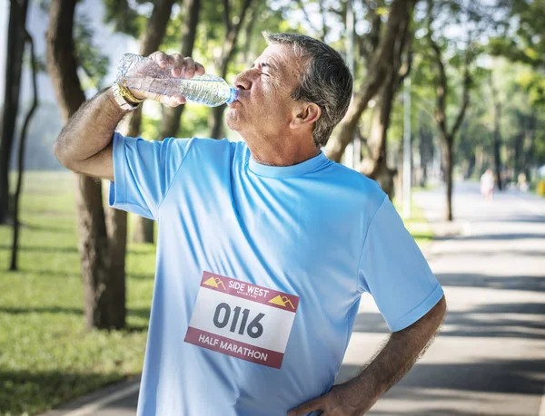年配の男性がマラソンの実行後水をリフレッシュ — ストック写真