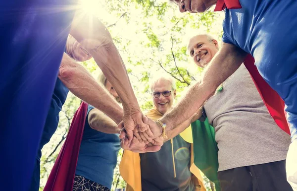 緑の夏の公園でスーパー ヒーローの衣装を着て 一緒に手を繋いで高齢チーム コンセプト — ストック写真