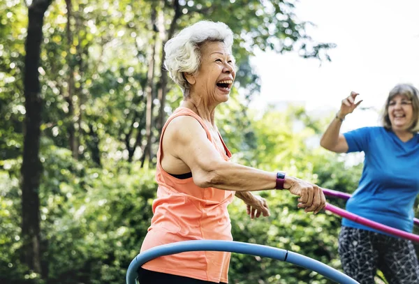 快乐的两位资深妇女在公园里练习呼啦圈 — 图库照片