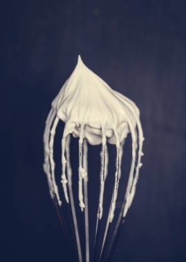 Close up of a wire whisk with whipped cream on top clipart
