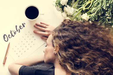 Uyuyan kadın kahve fincanı ve çiçekler ile Ekim takvim masada yatan yorgun 