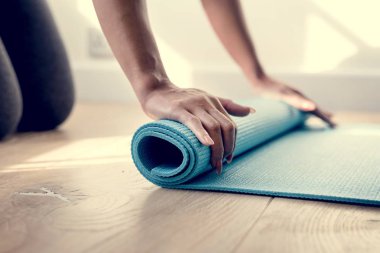 yoga mat ahşap zemin üzerinde haddeleme kadın görüntüsünü kırpılmış