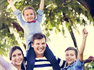 Aile parkı ve eller yukarı, baba omuzlarında oturan kızı eğleniyor