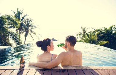 Havuzun kenarında bir bira olan genç çift