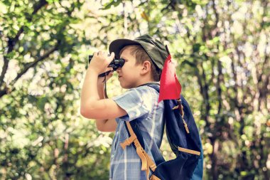 Sırt çantası ve kırmızı bayrak dürbün ormandaki bakarak küçük çocuk