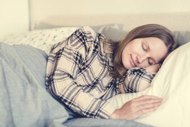 pijama battaniyenin altında yatakta uyuyan genç kadın
