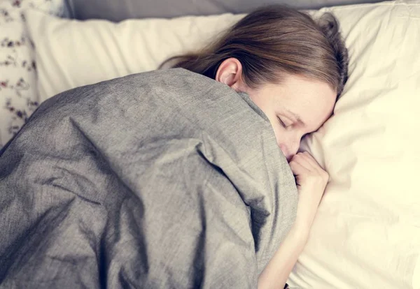 在床下睡觉的年轻妇女的顶部看法在毯子之下 — 图库照片