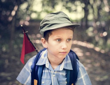 Küçük çocuk sırt çantası ve kırmızı bayrak, bir orman yoluyla hiking uzağa arıyorsunuz 