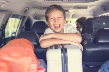 Araba gövde ile bakan bir arabanın arka koltuğunda küçük çocuk gülümseyen