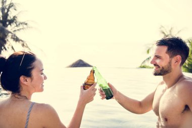 Havuzun kenarında bir bira olan genç çift