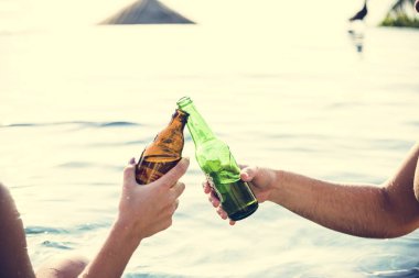 Havuzun kenarında bir bira olan genç çift