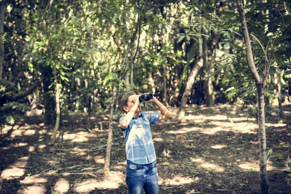 在森林里看着望远镜的男孩 — 图库照片