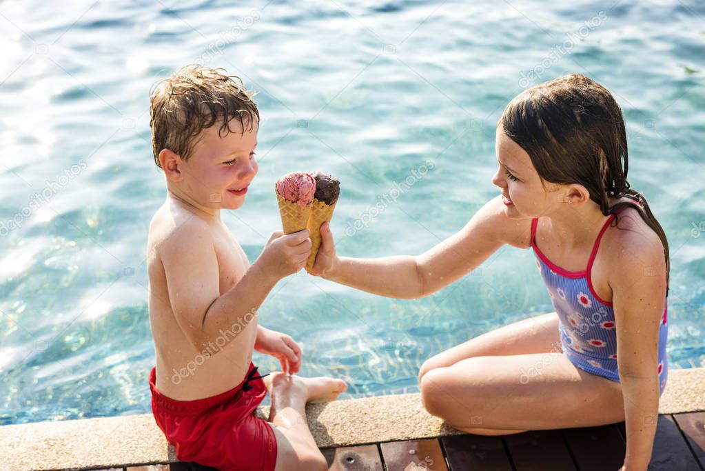 Kids toasting with ice creams at the poolside