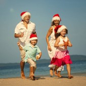 šťastná rodina v Santa klobouky baví na písečné pláži 