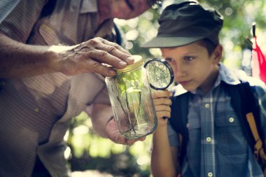 Çocuk bir bitki a magnifying cam kavanoza incelenmesi